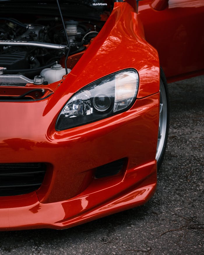 Detailed shot of a red sports car's front and open hood, showcasing sleek design.